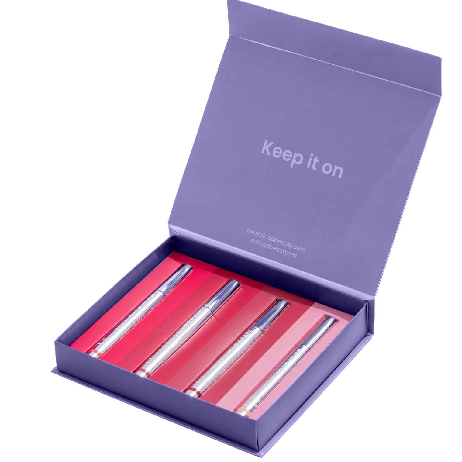 Stained lip stain discovery box with four Stay-On Lip Stain tubes in a purple ‘Keep it on’ gift packaging with transparent background