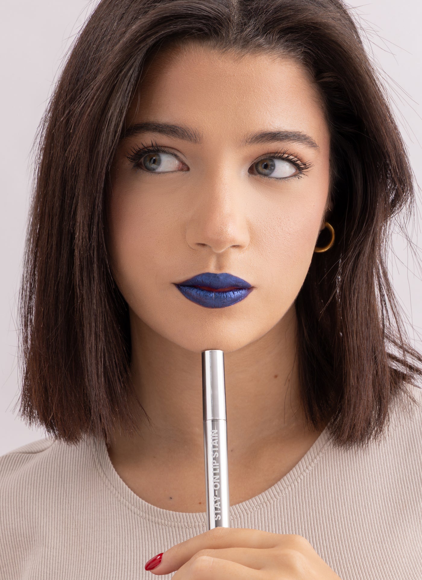 Model holding Stay-On Lip Stain while wearing blue shade